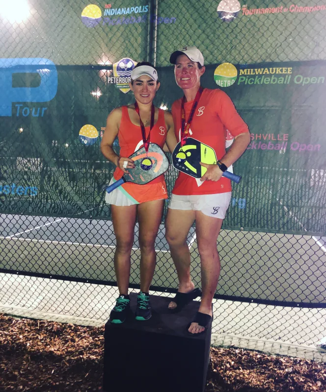 Sarah Ansboury and her doubles partner on court under lights